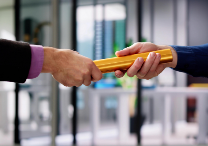 A couple of people in suits passing a baton in an office
