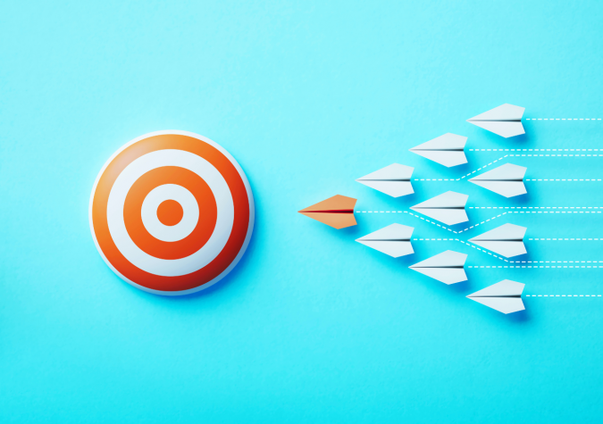 A paper airplane standing out from the crowd, targeting the bulls eye.