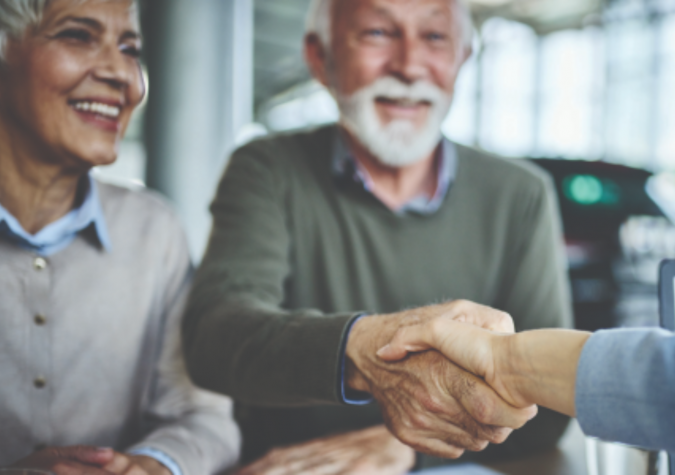 Couple shakes hands to close a sale at a dealership